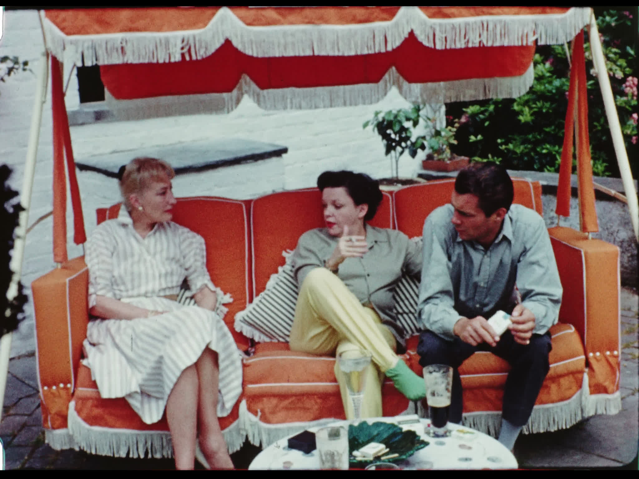 Dirk Bogarde, Judy Garland, and Kay Young on a Swing Set at Drummers Yard